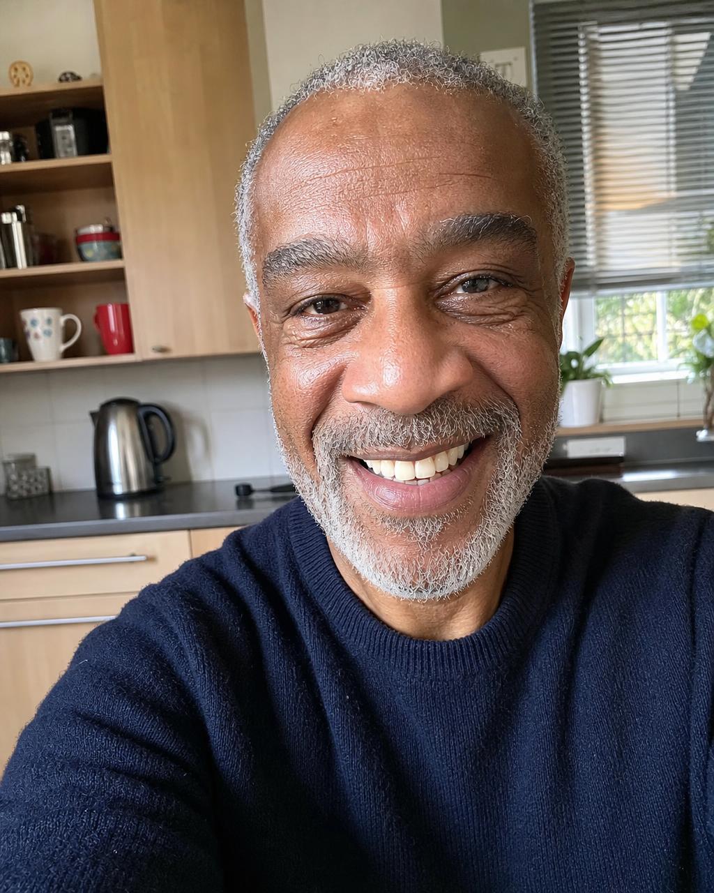 An older man on a recorded video call in a sunlit kitchen, seen through the FaceTime camera